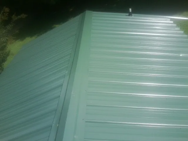 New green metal panels meeting at the ridge of a roof — Flat Roof Repair work by our crew in Clearwater