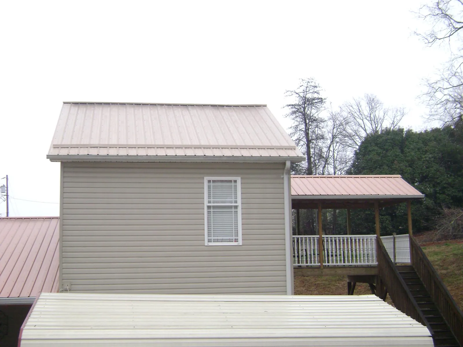 Tan metal roofs on a two story addition and attached porch, from a Roof Replacement job in Clearwater