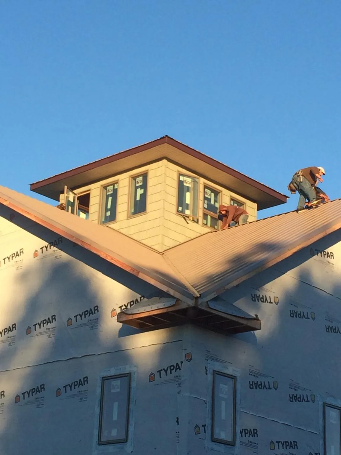 Roofers working around a rooftop cupola on a new metal roof at sunset — Roof Waterproofing in Clearwater by Roofing Brothers